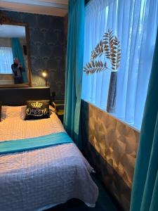 a bedroom with a bed and a window with blue curtains at Amstelmeer Kamer in Westerland
