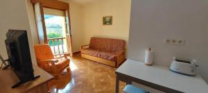 a living room with a tv and a chair at APARTAMENTOS RURALES PERNÚS in Colunga