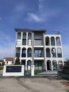a white building with a fence in front of it at LA TERRAZZA APARTMENTS - Sand & Green Apartments - DeltadelPo in Porto Viro