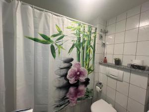 a bathroom with a shower curtain with a plant at Apartment Sebald in Ingolstadt