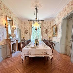 a dining room with a table with chairs and wallpaper at Domaine de Montclair in Pommiers