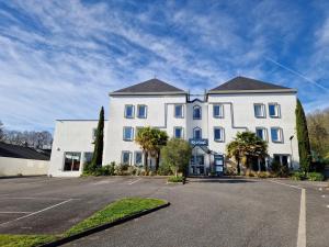 a large white building with palm trees in a parking lot at Kyriad Quimper Sud in Quimper