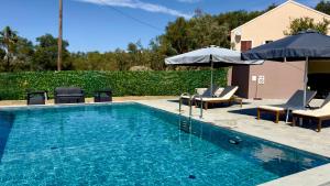a swimming pool with lounge chairs and umbrellas at Villa giannis in Vitalades