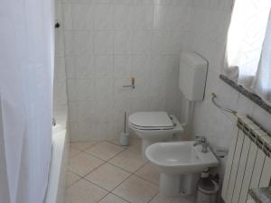 a white bathroom with a toilet and a sink at Rosario House in Comacchio