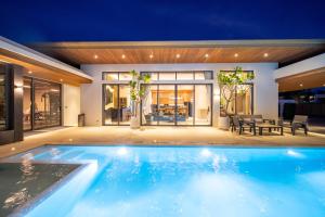 a swimming pool in front of a house at night at Ming Resort Phuket in Mai Khao Beach
