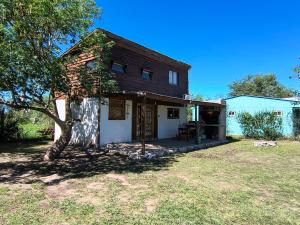 an old house with a porch and a tree at Cabaña Mitimay in Alta Gracia
