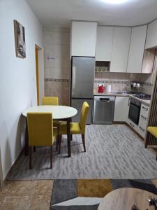 a kitchen with a table and yellow chairs in a room at Cosy Apartment in Podgorica - Fast WiFi & cable TV in Konik