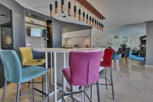 a kitchen with a bar with colorful bar stools at Villa d'Exception 330m Piscine 12x6 in Fontaines-Saint-Martin