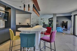 a kitchen with colorful chairs and a white table at Villa d'Exception 330m Piscine 12x6 in Fontaines-Saint-Martin