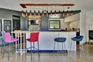 a kitchen with a bar with pink and blue stools at Villa d'Exception 330m Piscine 12x6 in Fontaines-Saint-Martin +49 photos