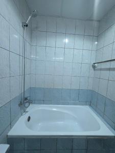 a bath tub in a tiled bathroom with a shower at Ajman Studio Downtown B2OO7 in Ajman  +6 photos