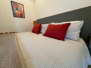 a bedroom with a bed with red and white pillows at Umbrella Street Home in Catania