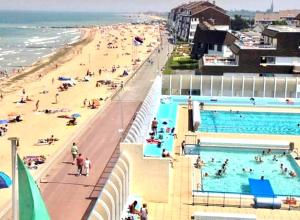 a beach with a large pool and a crowd of people at Luxy Room in Courseulles-sur-Mer