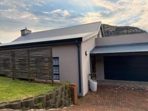 a white house with a garage and a fence at Belo Villa Clarens in Clarens