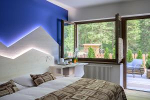 a bedroom with a bed and a large window at Hotel Garni Roberta in Malga Ciapela