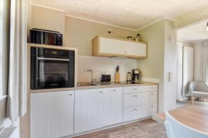 a kitchen with white cabinets and a microwave at Ferienhaus Boddenlust 24 Feriendorf Klein Stresow Rügen by ruyastay in Putbus +5 photos