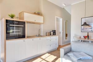 a kitchen with white cabinets and a couch at Ferienhaus Strandbude Feriendorf 32 Klein Stresow Rügen by ruyastay in Putbus
