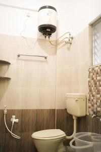 a bathroom with a toilet and a light on the wall at Hotel BMR Stay in Pollāchi +29 photos