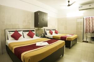 a hotel room with two beds with red pillows at Hotel BMR Stay in Pollāchi