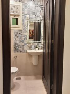 a bathroom with a sink and a toilet and a mirror at pyramids view luxury apartment in ‘Ezbet `Abd el-Ḥamîd