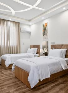 two beds in a bedroom with white walls and wooden floors at pyramids view luxury apartment in ‘Ezbet `Abd el-Ḥamîd