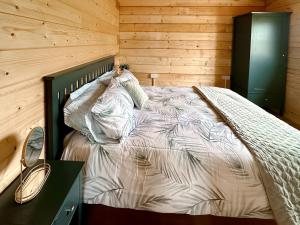 a bedroom with a bed in a wooden room at Wind Hall Log Cabin in Gosforth +7 photos