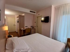 a bedroom with a white bed and a table at Hotel Chiaraluna in Civitanova Marche