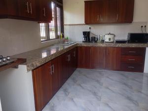 a kitchen with wooden cabinets and marble counter tops at Edelweiss Living Negombo in Negombo