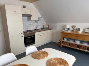 a kitchen with white cabinets and a table and chairs at Ferienwohnung Jutta u. Andreas Arenz in Minderlittgen +7 photos