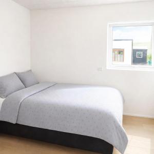 a white bedroom with a bed and a window at Rogvi's new appartment in Klaksvík