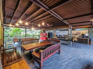 a dining room with a table and benches and a kitchen at Templer Park Rainforest Retreat TPRR in Rawang