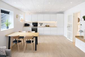 a kitchen with white cabinets and a wooden table and chairs at Rogvi's new appartment in Klaksvík