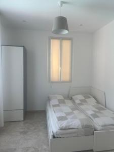 a white bedroom with a bed and a window at Katy in Nice