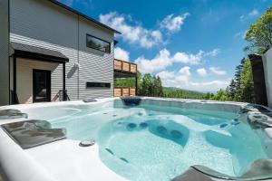 a hot tub in the backyard of a house at Käbane Horizon Boréal - Le Belvédère in Les Éboulements