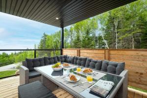 a patio with a table and chairs on a deck at Käbane Horizon Boréal - Le Belvédère in Les Éboulements