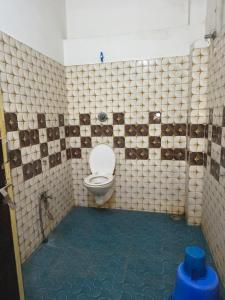 a bathroom with a toilet in a tiled room at Hotel Parinay Vatika in Deoghar