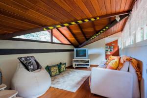 a living room with a couch and a tv at PASSAREDO - Casa de Campo Fazenda Inglesa in Araras Petropolis