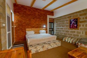 a bedroom with a bed and a brick wall at Jabulani Moshi in Msaranga +19 photos
