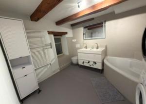 a white bathroom with a tub and a sink and a bath tub at Rooms4Rent in Bottmingen