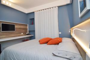 a bedroom with blue walls and a bed with orange pillows at Bed In Centro in Naples
