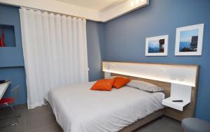 a bedroom with blue walls and a bed with orange pillows at Bed In Centro in Naples