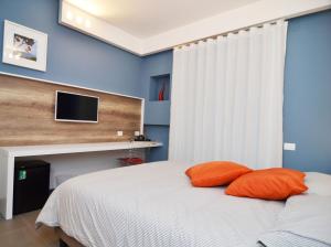 a bedroom with a bed with orange pillows and a tv at Bed In Centro in Naples