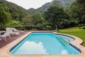 einen großen blauen Pool mit einem Tisch und Stühlen in der Unterkunft PASSAREDO - Casa de Campo Fazenda Inglesa in Araras Petropolis