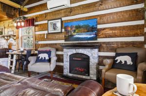 a living room with a fireplace and a tv on a wall at Creekside Hideout in Cosby