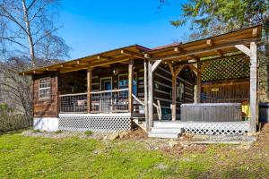 a wooden house with a porch on a grass field at Creekside Hideout in Cosby
