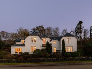 ein großes weißes Haus mit eingeschalteten Lichtern in der Unterkunft Ards House in Oban