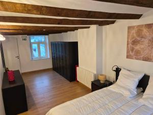 a bedroom with a white bed and a wooden ceiling at Le Fond du Village in Solre-Saint-Géry