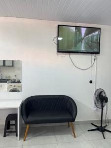 a tv hanging on a white wall with a bench at Kitnet aconchegante próximo a unesp in Botucatu