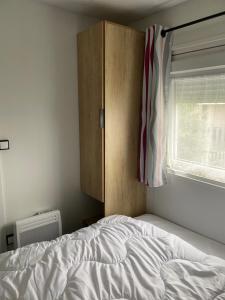 a bedroom with a bed and a cabinet and a window at Bungalow 6 personnes in Équihen-Plage
