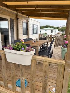a deck with a table and a pot of flowers at Bungalow 6 personnes in Équihen-Plage